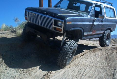 1986 Ford Bronco - This lifted Ford Bronco navigates a sandy incline, its off-road capabilities.