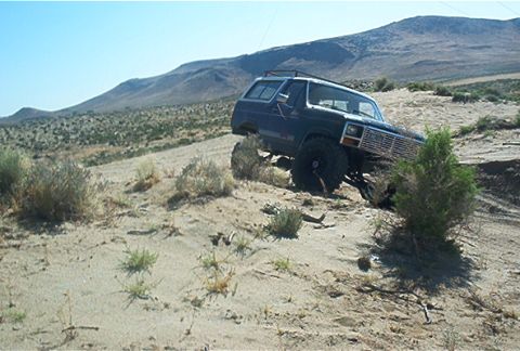 1986 Ford Bronco - This 1980s Ford Bronco navigates a steep, sandy incline under a clear blue sky.