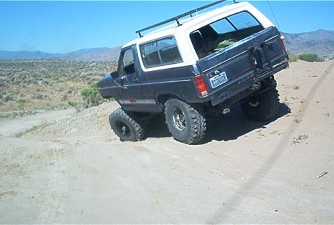 1986 Ford Bronco - This 1986 Ford Bronco is tackling a steep dirt hill with its tires digging in.