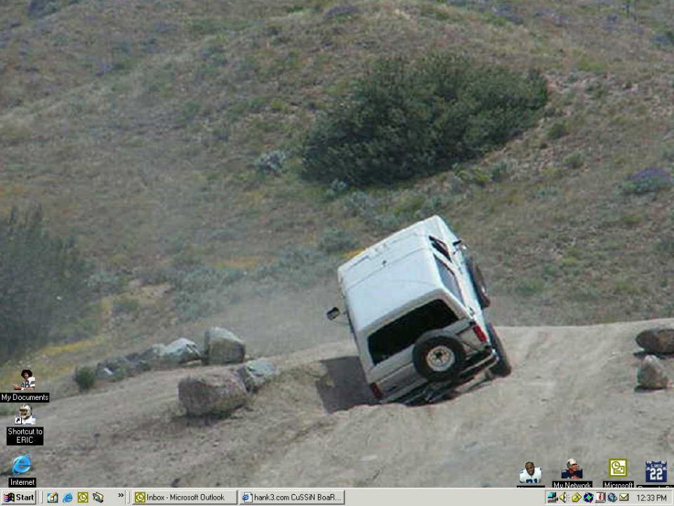 White van tilted on its side on a dirt hill with rocks