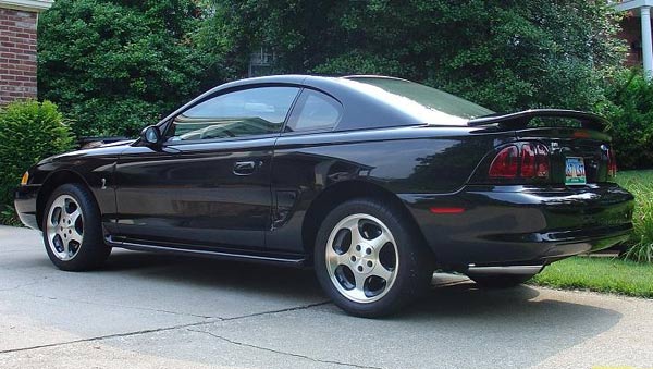Black coupe with a spoiler, side view, showing alloy wheels and tinted windows