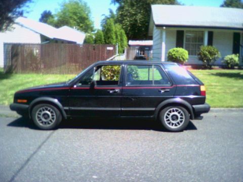 1987 Volkswagen Golf - Side profile of a black 1987 Volkswagen Golf parked on a residential street.
