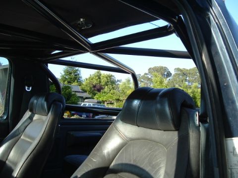 1989 Ford Bronco - Interior view of a vehicle's roll cage and seats, with a glimpse of the outdoors through the windows.