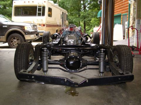 1967 Pontiac GTO - Car frame and engine assembly in a garage setting with other vehicles present.
