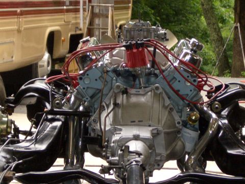 1967 Pontiac GTO - Close-up view of an engine and chassis components, with visible red spark plug wires and a silver carburetor.