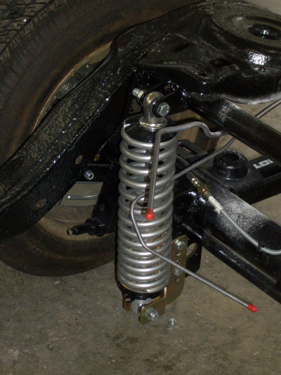 QA1 coilover shock with silver spring mounted to black rear frame rail and control arm