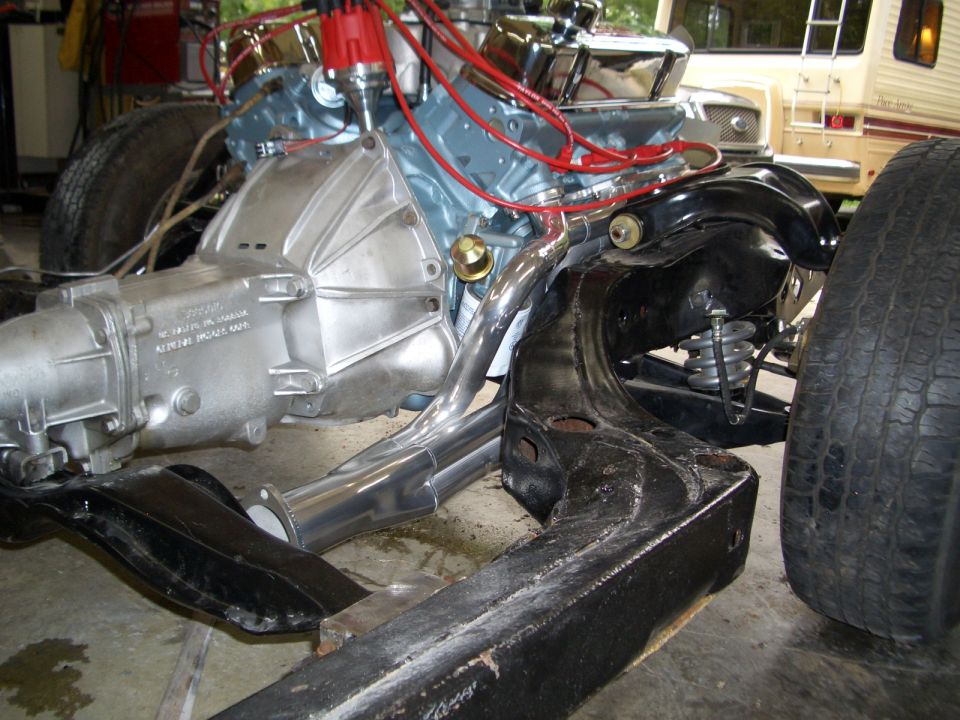 Light blue Pontiac V8 and automatic transmission mounted in bare frame with chrome headers
