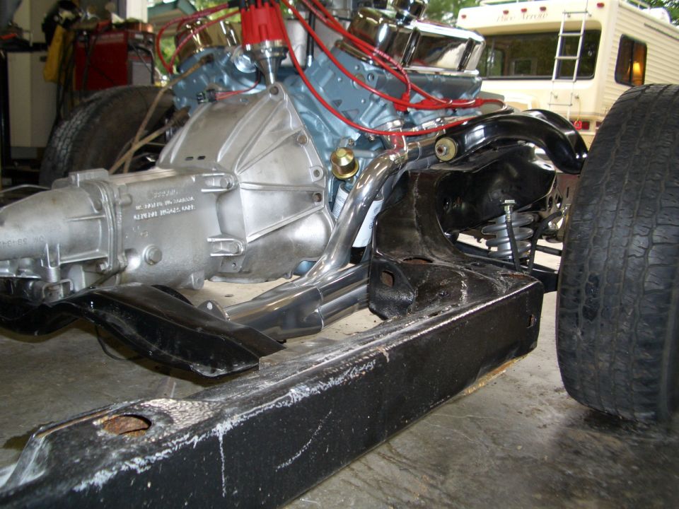 Light blue V8 and automatic transmission mounted in bare black-painted chassis
