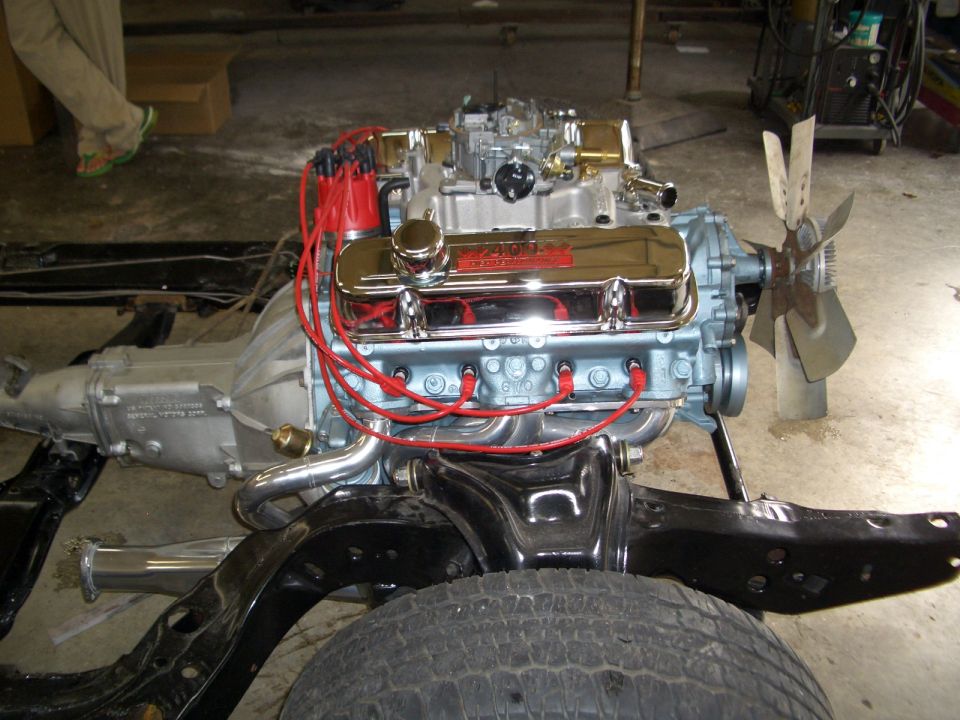Light blue Pontiac 400 V8 with chrome valve covers and red plug wires on a bare frame