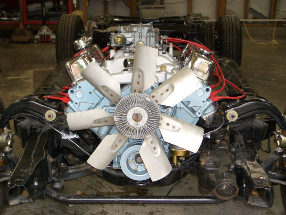 Rebuilt light blue V8 with chrome valve covers and clutch fan in a bare front subframe