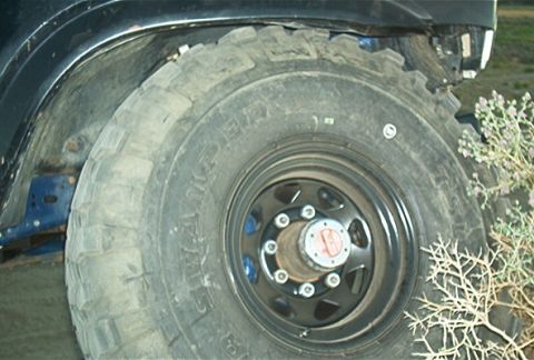 1986 Ford Bronco - Close-up of a vehicle's wheel and tire, showing off-road tread and a black rim with a prominent hub.