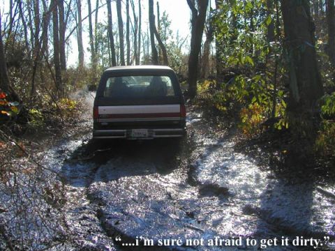 1988 Ford Bronco - A black Ford Bronco navigates a muddy, wooded path.