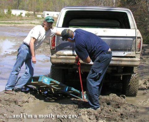 1988 Ford Bronco - Two men attempt to free a stuck Ford Bronco from the mud using a jack and a wooden pallet.