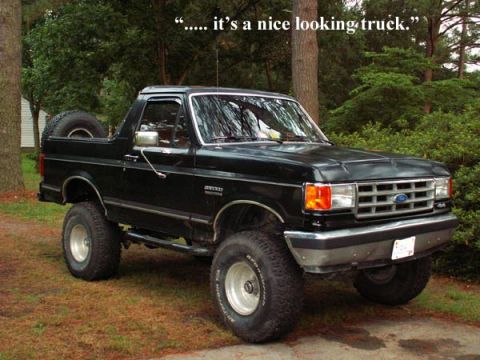 1988 Ford Bronco - This black 1988 Ford Bronco is shown in a 3/4 front view, parked outdoors with trees in the background.