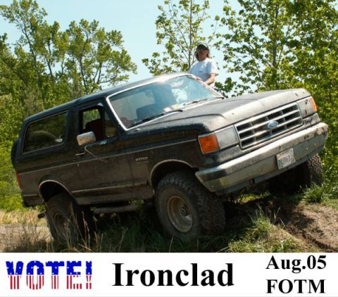1988 Ford Bronco - A dark Ford Bronco navigates an off-road trail on a sunny day.