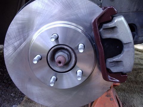 2000 Ford Taurus - A close-up view of a car's brake rotor and caliper assembly, with visible text from SuperMotors.net.