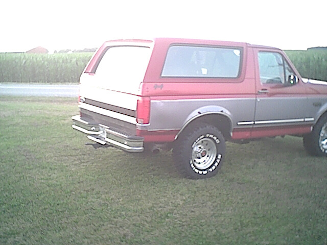 Red and gray Ford Bronco parked on grass, rear view