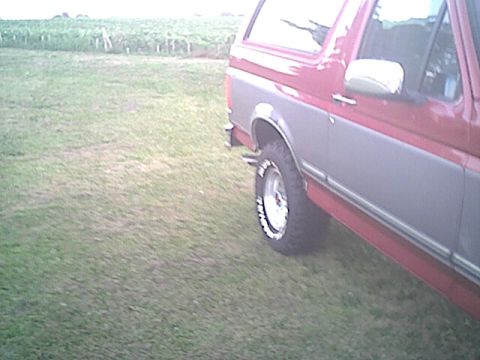 1994 Ford Bronco - A two-tone Ford Bronco is parked on a grassy field.