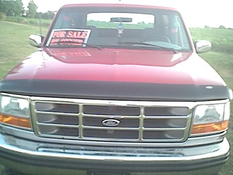 1994 Ford Bronco - Front view of a red 1994 Ford Bronco with a 'For Sale' sign in the windshield.
