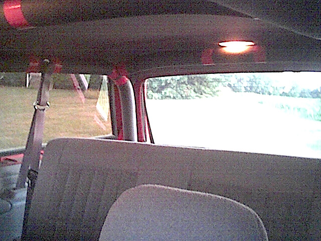 View from back seat of an SUV, looking forward. Interior light on, trees visible through windows