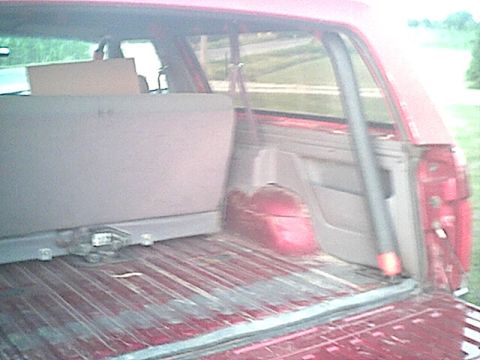1994 Ford Bronco - The cargo area of a red SUV is shown with the rear seats folded down and a box placed inside.