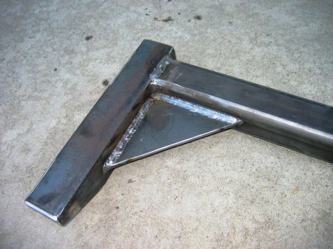 1985 Ford Bronco - This photo shows a custom-fabricated steel bracket with visible welds, resting on a concrete floor.