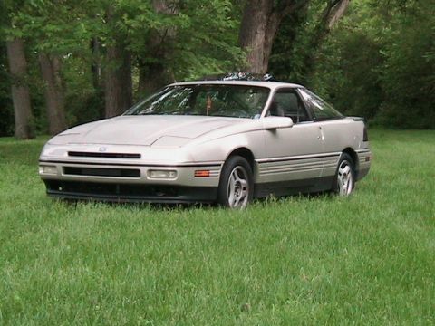 1989 Ford Probe - A silver 1989 Ford Probe GT is parked on a grassy lawn with trees in the background.