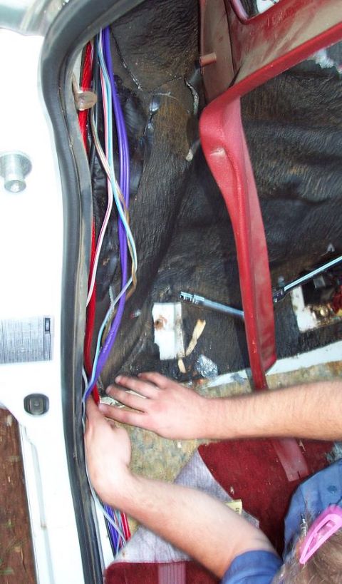 1985 Ford LTD Crown Victoria - A person is working on the wiring harness inside the car's interior.