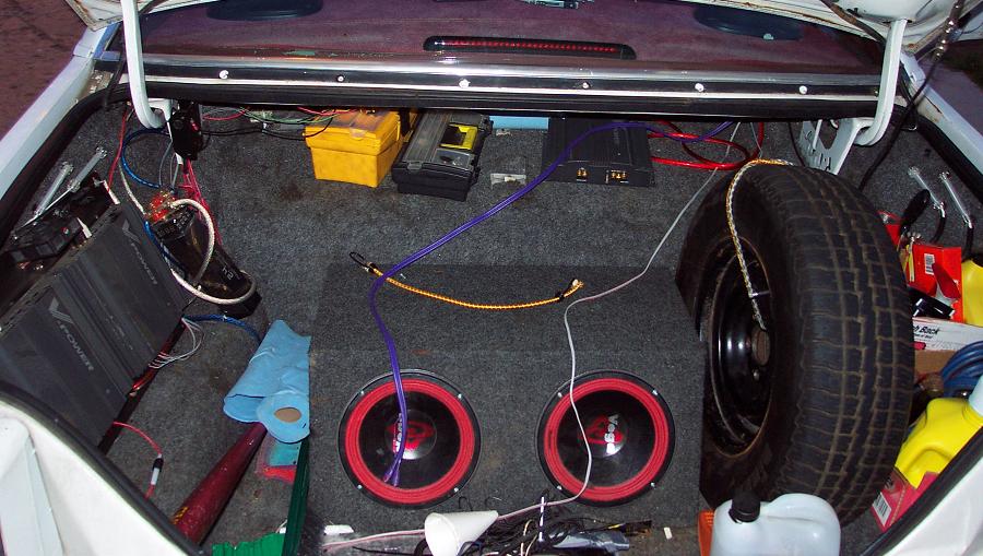 Trunk interior with two subwoofers, amplifiers, and spare tire