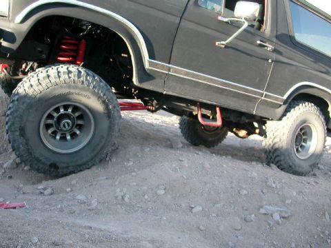 1984 Ford Bronco - This 1984 Ford Bronco is shown with modifications for off-road use, including large tires and visible red suspension components.