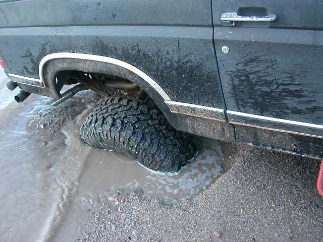 1984 Ford Bronco rear tire stuck in mud and water