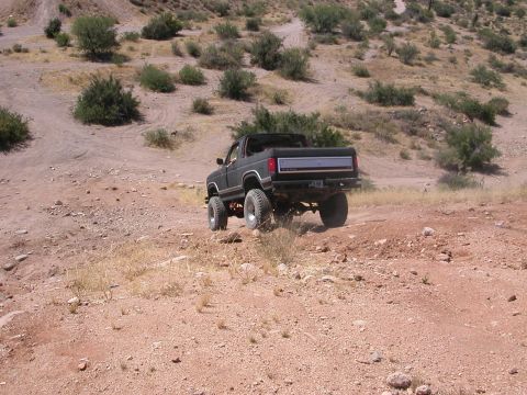 1984 Ford Bronco - This dark-colored Ford Bronco appears to be from the early 1980s, seen here navigating a dusty, off-road trail.