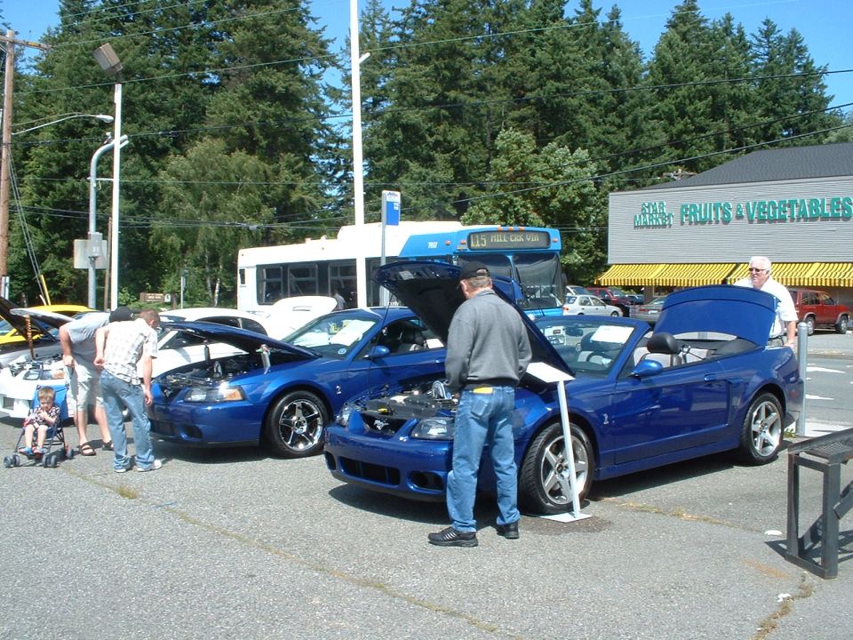 Blue convertible sports car with hood open, parked next to another blue sports car