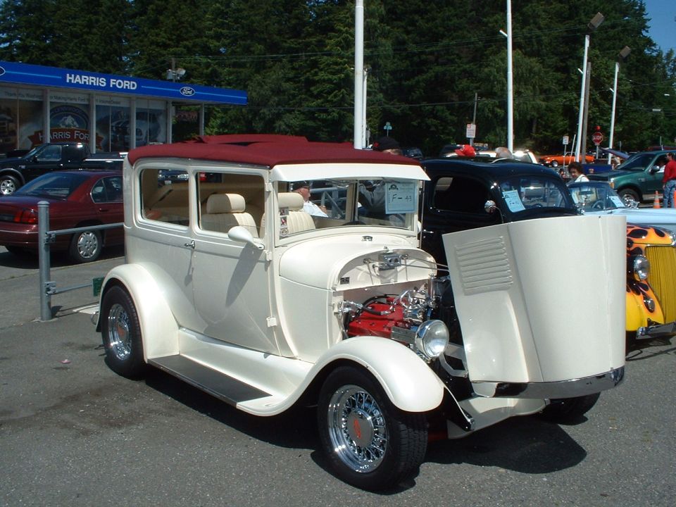 White vintage sedan, maroon roof, exposed red engine, parked at Harris Ford