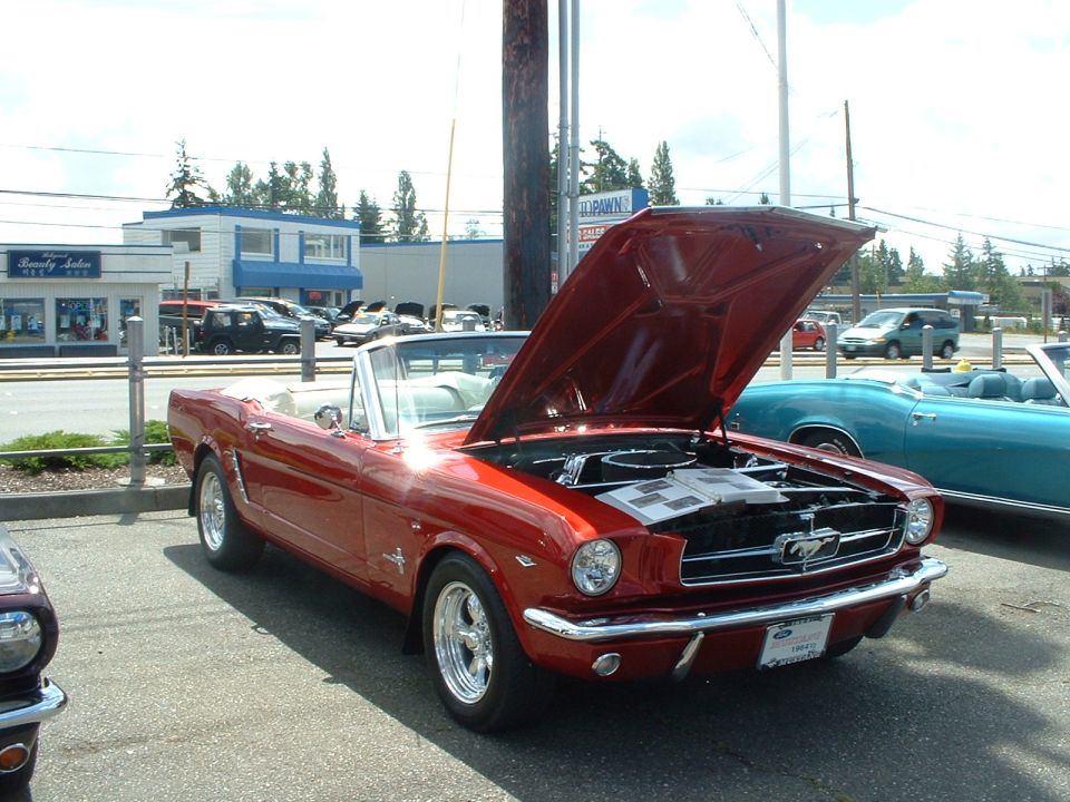 Red 1965 Ford Mustang convertible with hood open, showing engine