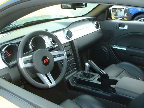 1999 Ford Crown Victoria - The interior of a yellow vehicle is shown, the dashboard, steering wheel, and center console.