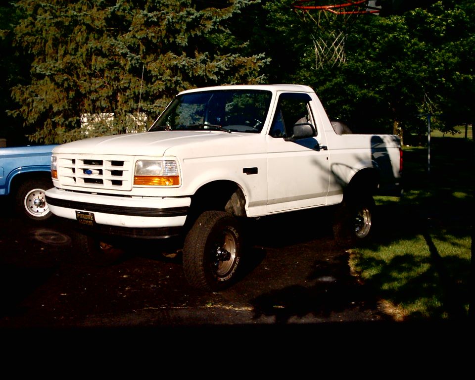 White Ford Bronco, lifted, with aftermarket wheels, parked outdoors