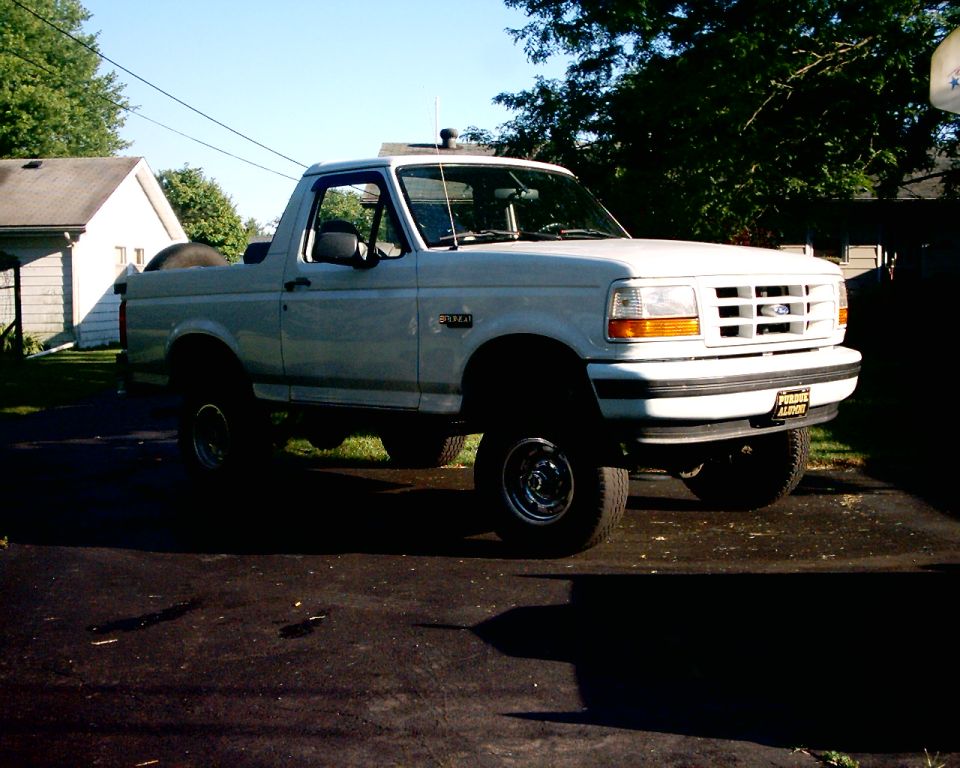 White 1996 Ford Bronco parked on asphalt driveway, front 3/4 view, clear sky