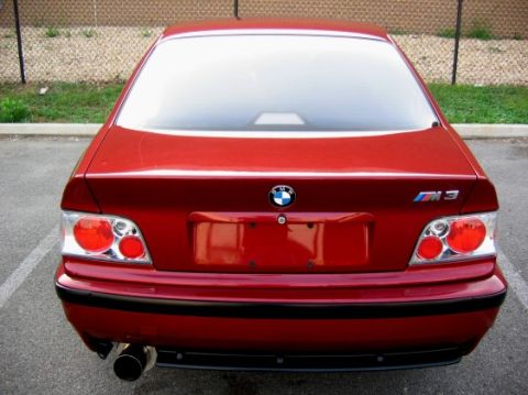 1995 BMW M3 - The rear of a red BMW M3 sedan is shown, its distinctive taillights and M3 emblem.