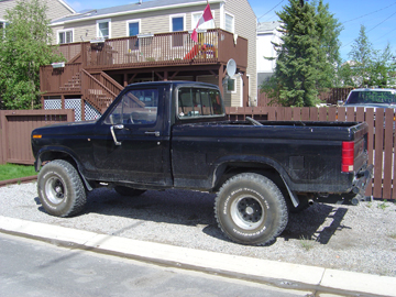 1986 Ford F-150 - Black 1986 Ford F-150 pickup truck parked outside a residential building.