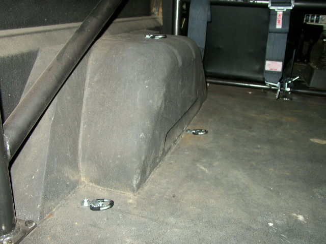 Vehicle interior floor with tie-down rings and a roll cage bar