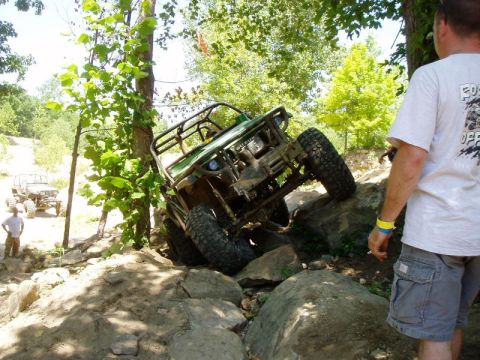 1992 Ford Bronco - An off-road vehicle navigates a challenging rocky terrain with a person watching.