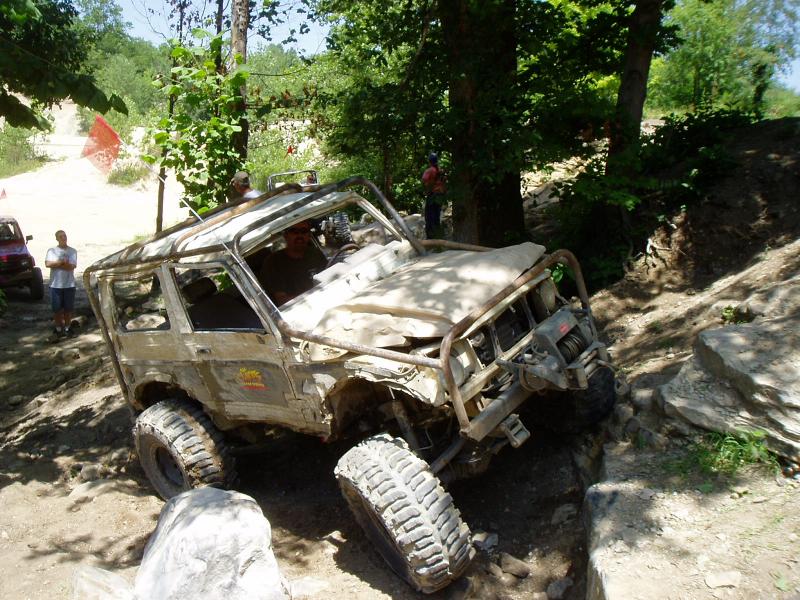 Mud-covered off-road vehicle with roll cage on rocky terrain