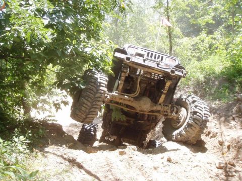 1992 Ford Bronco - An off-road vehicle navigates a steep, dirt incline with one wheel lifted.