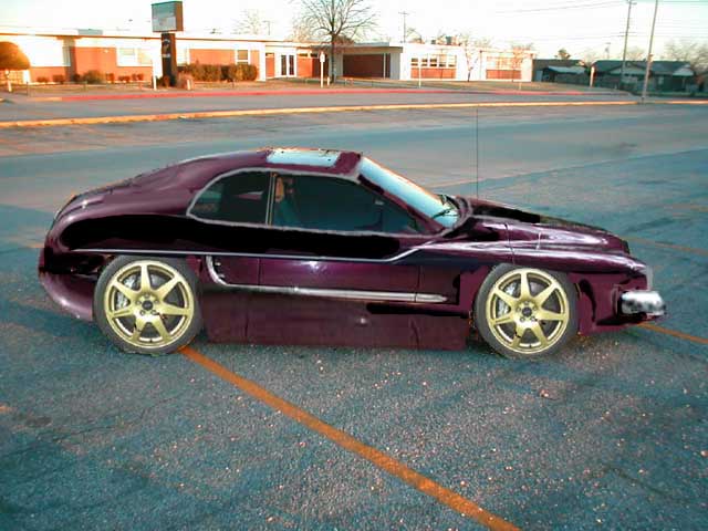 purple coupe with gold wheels parked on asphalt, building in background