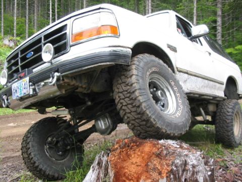 1995 Ford Bronco - A white Ford Bronco navigates an obstacle course in a wooded area.