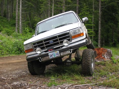 1995 Ford Bronco - This modified Ford Bronco is shown navigating an off-road obstacle in a wooded area.