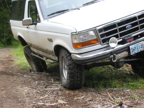 1995 Ford Bronco - This 1995 Ford Bronco is shown with its front-right tire at an angle on a dirt path, highlighting its off-road capabilities.