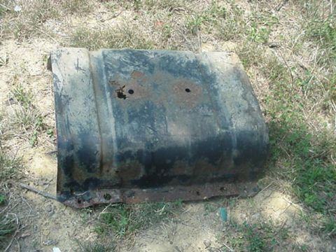 1988 Ford Bronco - This heavily rusted metal part, possibly a fuel tank or fender component, is shown outdoors on the ground.