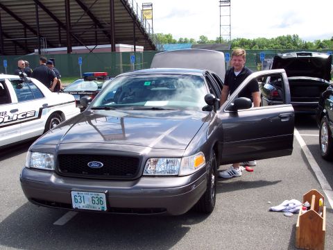 2001 Ford Crown Victoria - A gray 2001 Ford Crown Victoria police car is displayed with its door open, alongside another police vehicle.